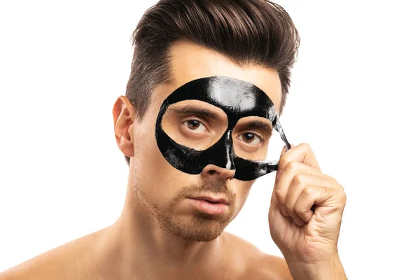 Fiatal fickó egy fekete szén maszkot az arcán a fehér háttérben — Stock Fotó