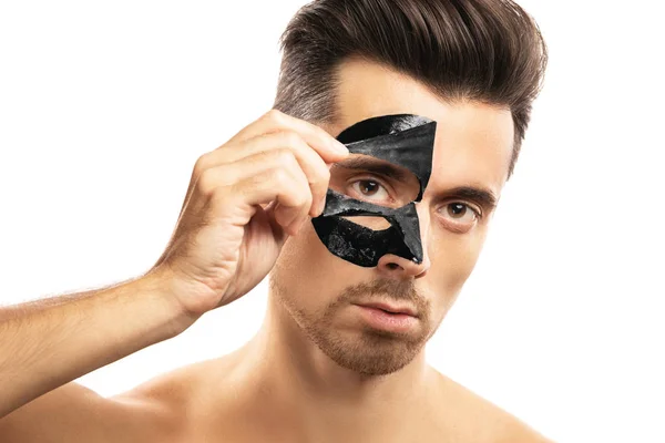 Νέος τύπος με μια μαύρη μάσκα άνθρακα στο πρόσωπό του σε λευκό πίσω — Φωτογραφία Αρχείου
