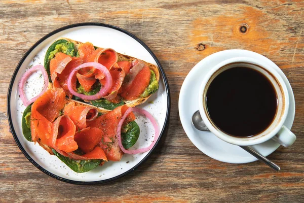 Delicious toasts with smoked salmon, avocado and basil leaves — Stock Photo, Image