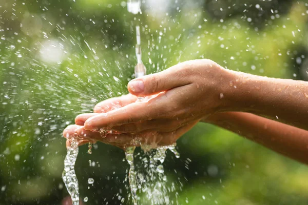 Manos femeninas mojadas y salpicaduras de agua clara — Foto de Stock