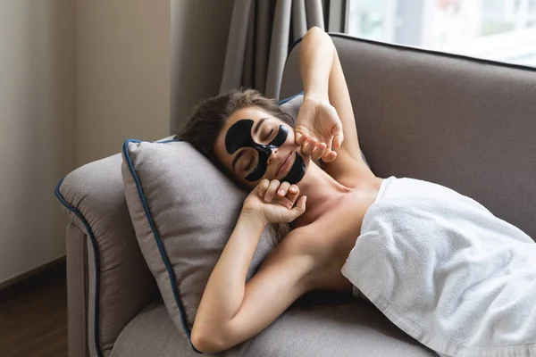 Güzel kadın siyah peel-off maskesi ile evde rahatlatıcı — Stok fotoğraf