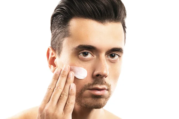 Giovane uomo sta applicando crema idratante sul suo viso — Foto Stock