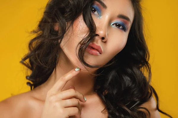 Asiatische Frau mit einem schönen lockigen Haar und Make-up auf gelb ba — Stockfoto