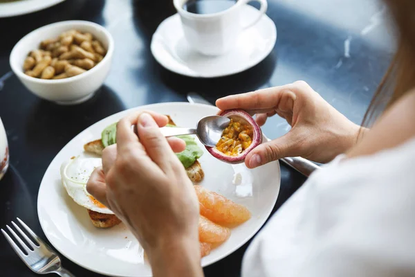 Café da manhã saudável - Mulher está comendo maracujá fresco . — Fotografia de Stock