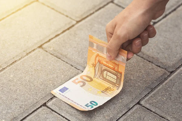 Donna sta raccogliendo cinquanta banconote in euro da terra . — Foto Stock