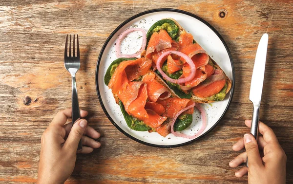 Kadın elleri ve füme somon, avokado ile lezzetli tost — Stok fotoğraf