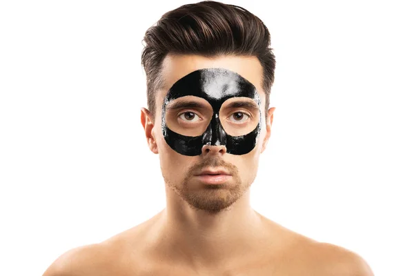 Νέος τύπος με μια μαύρη μάσκα άνθρακα στο πρόσωπό του σε λευκό πίσω — Φωτογραφία Αρχείου