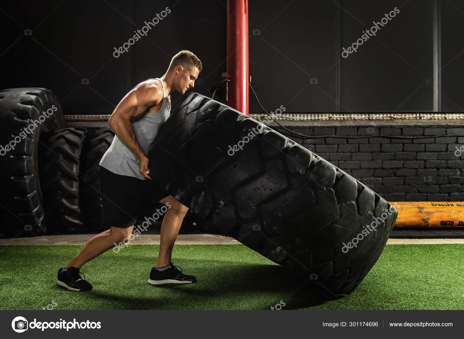 Strong sportsman doing a tire flip exercise Stock Photo by