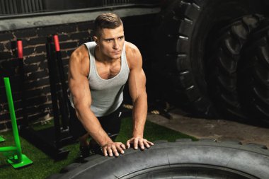 Genç kaslı adam lastik üzerinde push up yapıyor