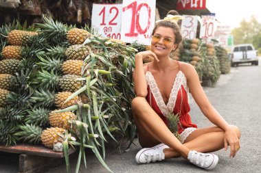 Yerel Tha üzerinde ananas yığını ile genç ve mutlu kadın