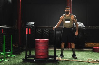 Spor salonunda yaptığı egzersiz sırasında kilo yelek giyen sporcu