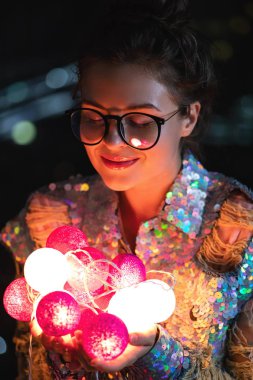 Payetli parlayan ceket giyen mutlu kadın ışık tutuyor