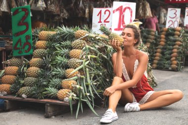 Yerel Tha üzerinde ananas yığını ile genç ve mutlu kadın