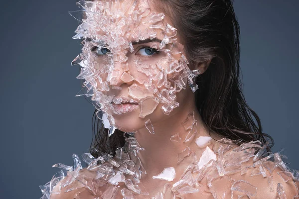 Женское лицо, покрытое большим количеством маленьких кусочков стекла или льда — стоковое фото