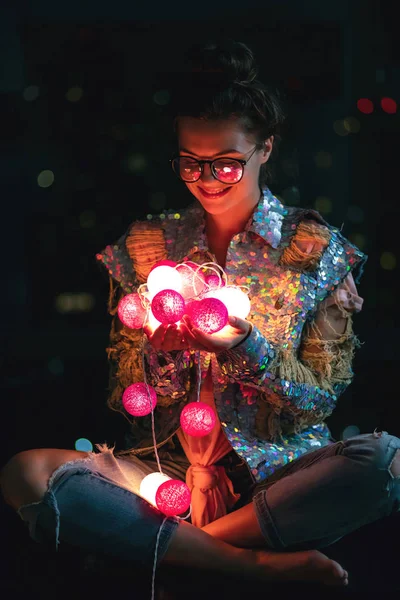 Mulher feliz vestindo casaco brilhante com lantejoulas está segurando luz — Fotografia de Stock