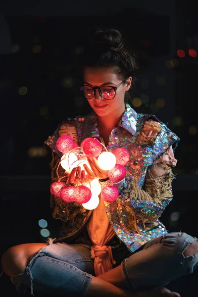Mulher feliz vestindo casaco brilhante com lantejoulas está segurando luz — Fotografia de Stock