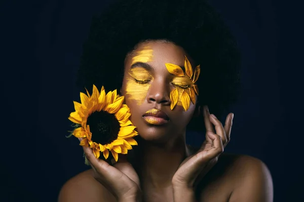 Afrikaanse vrouw met een zonnebloem en creatieve make-up op haar gezicht — Stockfoto