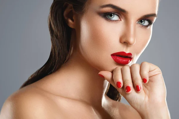 Retrato de una hermosa mujer joven con un lápiz labial rojo y uñas p — Foto de Stock