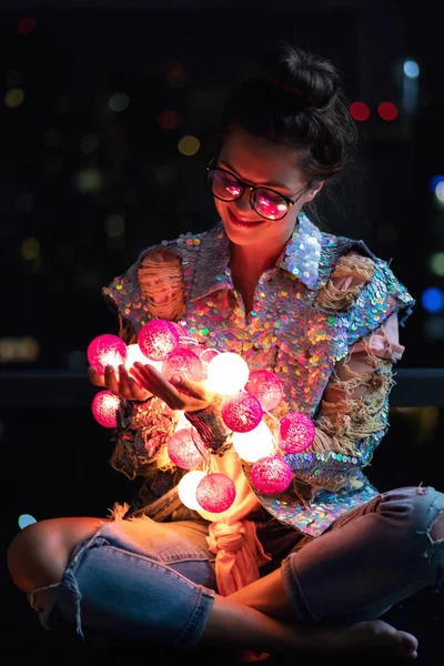 Mulher feliz vestindo casaco brilhante com lantejoulas está segurando luz — Fotografia de Stock