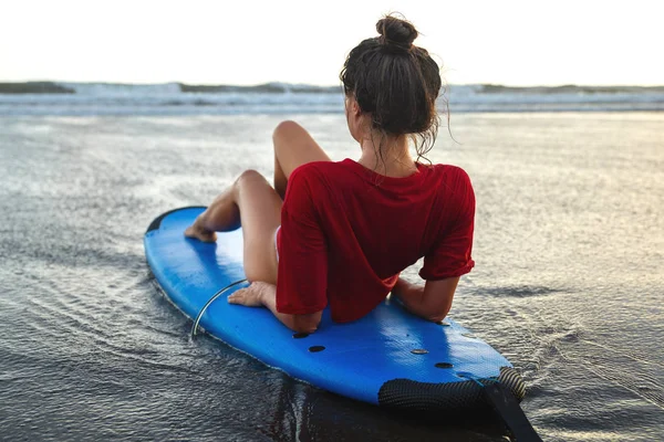 Mulher sentada na prancha de surf na praia depois de sua sessão de surf — Fotografia de Stock