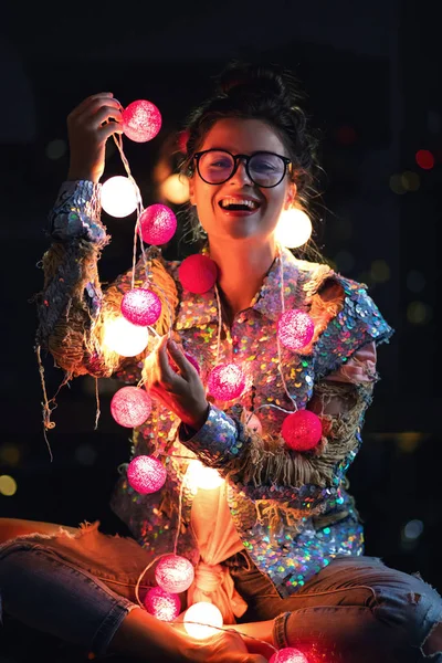 Happy woman wearing glowing jacket with sequins is holding light — Stock Photo, Image