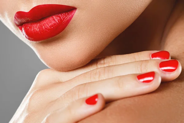 Beauty and cosmetics. Female mouth and nails with red manicure a