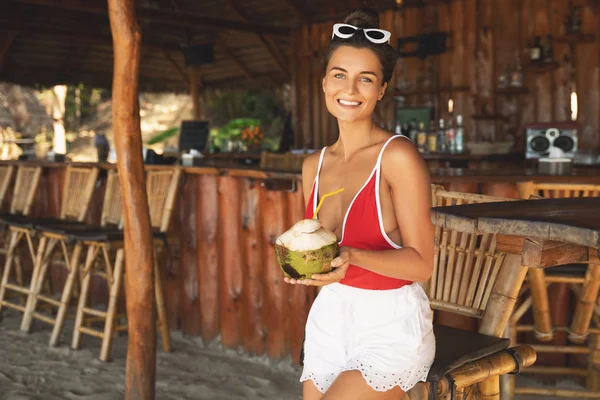 Young and sexy woman sitting in authentic beach bar with a cocon — Stock Photo, Image