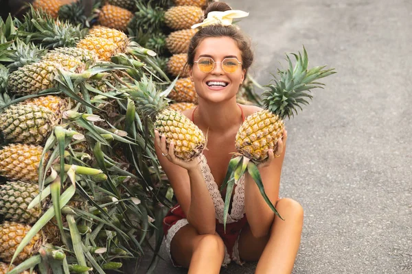 Mujer joven y feliz con una pila de piñas en el Tha local — Foto de Stock