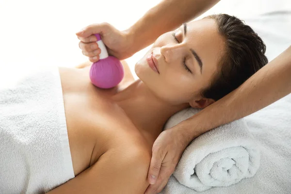 Mujer está disfrutando de la terapia de masaje asiático con compresa de hierbas —  Fotos de Stock