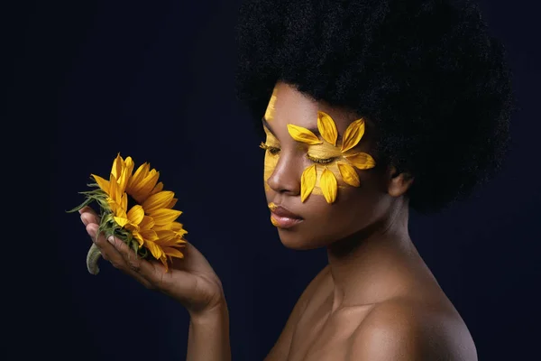 Mulher africana com um girassol e maquiagem criativa em seu rosto — Fotografia de Stock