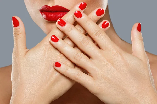 Beauty and cosmetics. Female mouth and nails with red manicure a