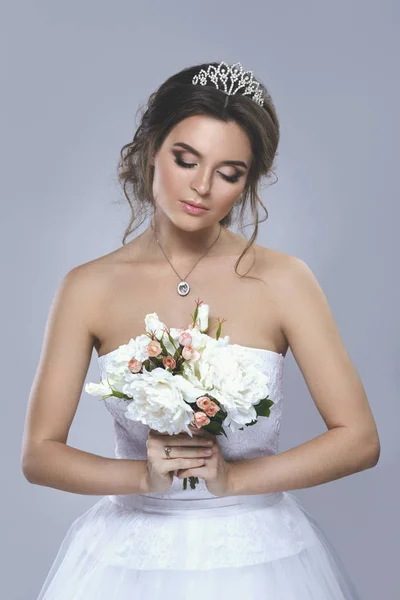 Porträt einer jungen schönen Braut mit einem Blumenstrauß — Stockfoto
