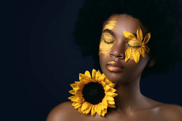 Afrikaanse vrouw met een zonnebloem en creatieve make-up op haar gezicht — Stockfoto