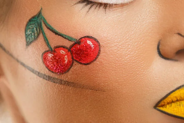 Female face with a drawing  of cherry berries