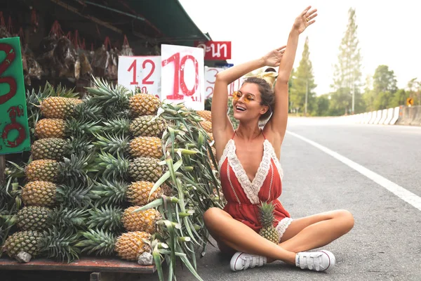 Young and happy woman with a pile of pineapples on the local Tha — Stock Photo, Image