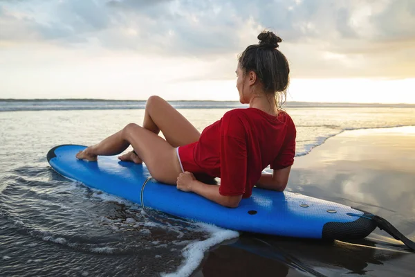 Mulher sentada na prancha de surf na praia depois de sua sessão de surf — Fotografia de Stock