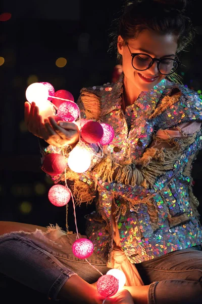 Lycklig kvinna bär glödande jacka med paljetter håller ljus — Stockfoto