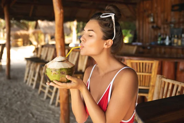Mujer joven y sexy sentada en un auténtico bar de playa con un cocon — Foto de Stock