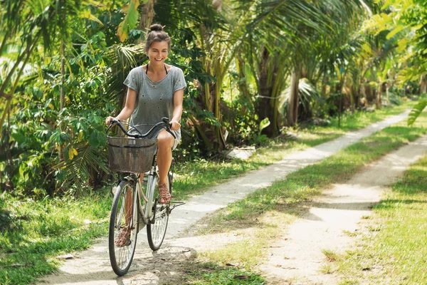Szczęśliwa kobieta jeździ rowerem w tropikalnym ogrodzie w gorącym lecie — Zdjęcie stockowe
