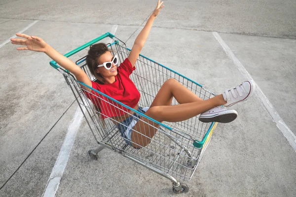 Mujer dentro de un carrito de compras en el aparcamiento del supermercado — Foto de Stock