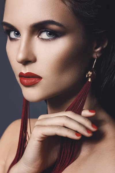 Mulher deslumbrante com uma bela maquiagem vestindo longos brincos vermelhos — Fotografia de Stock
