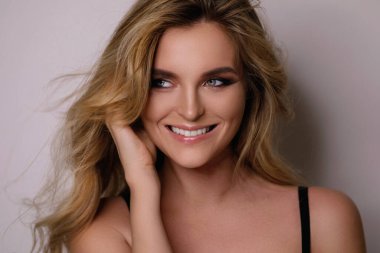 Güzel kıvırcık saçlı ve profesyonel makyajlı muhteşem bir kadının portresi.