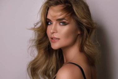 Güzel kıvırcık saçlı ve profesyonel makyajlı muhteşem bir kadının portresi.