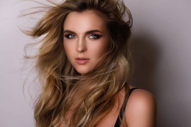 Güzel kıvırcık saçlı ve profesyonel makyajlı muhteşem bir kadının portresi.