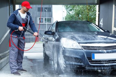 Profesyonel oto yıkama işçisi müşterinin arabasını yıkıyor.