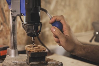 Marangoz atölyesindeki matkap üzerinde çalışıyor.