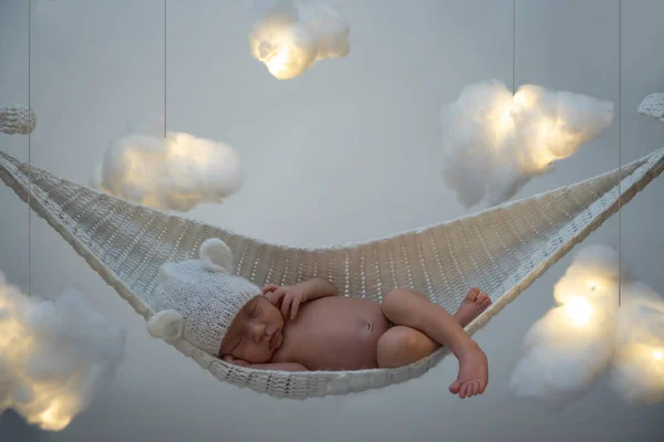 Cute little baby sleeping in the hammock with a lot clouds made of cotton wool