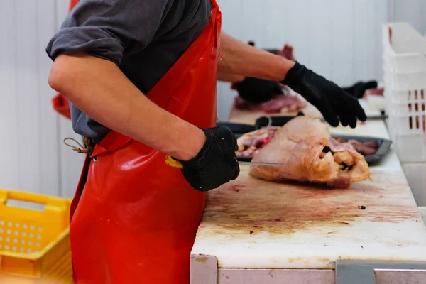 Slager in rode schort hakken van vlees van pluimvee. Snijden shop van boerderij markt. — Stockfoto