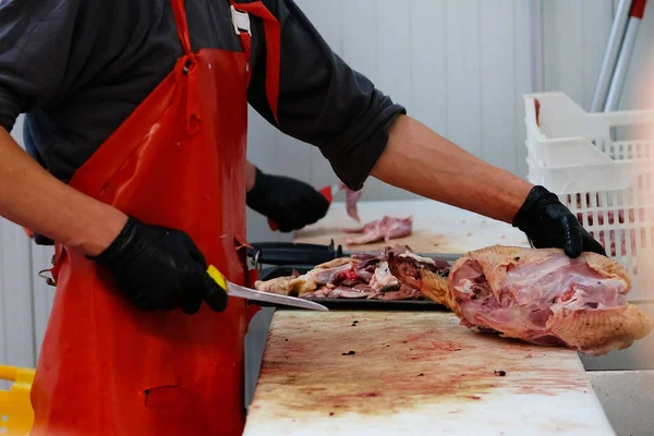 Carniceiro com avental vermelho a cortar carne de pato. Loja de corte do mercado agrícola . — Fotografia de Stock