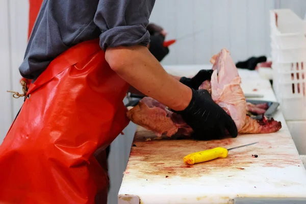 Slager in rode schort eend vlees hakken op teller van snijden winkel op boerderij markt. — Stockfoto